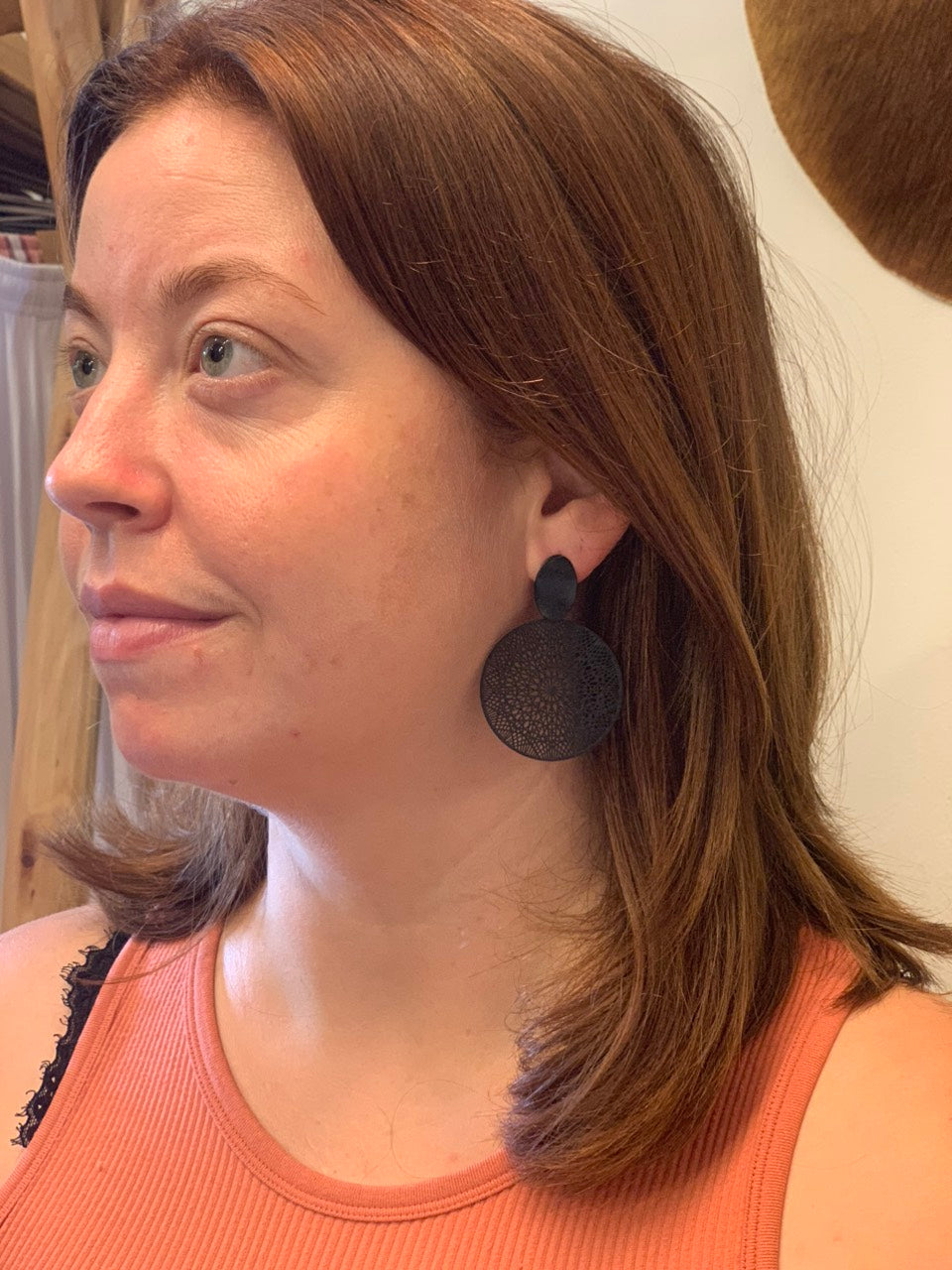 woman wearing black mandala earrings.