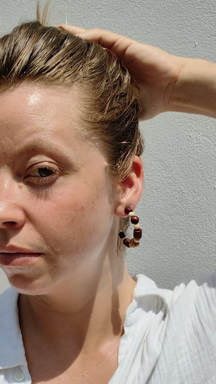Woman wearing wooden bead hoop earrings.