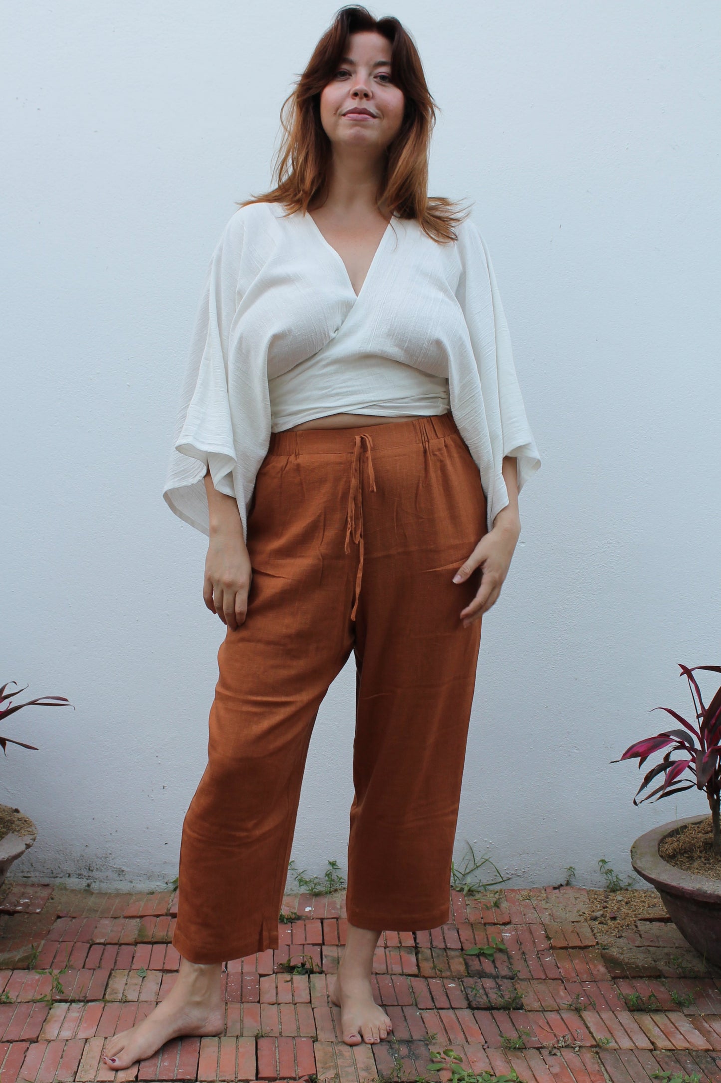 A boho style white wrap top and brown linen pants.