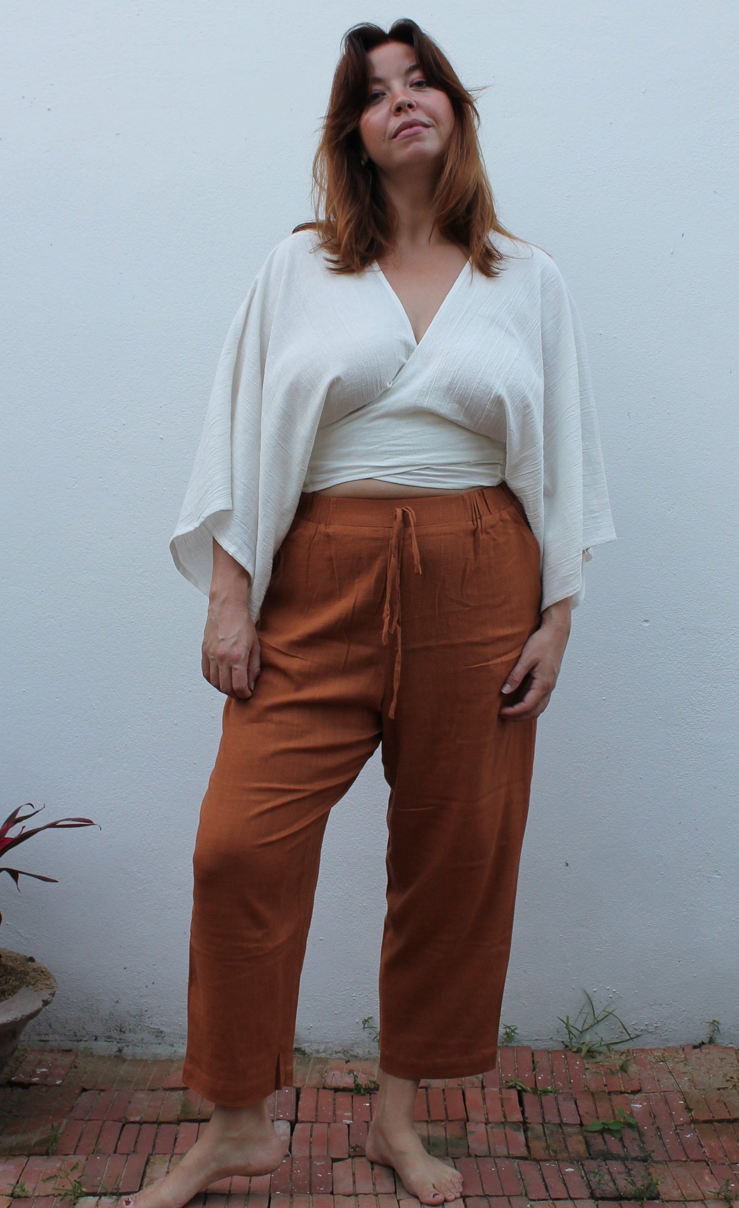 A boho style white wrap top and brown linen pants.