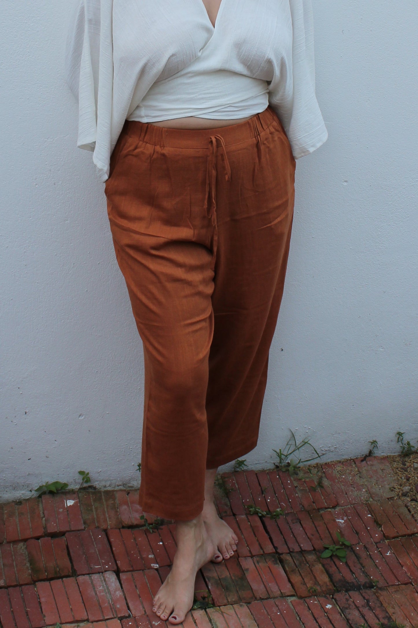 A boho style white wrap top and brown linen pants.