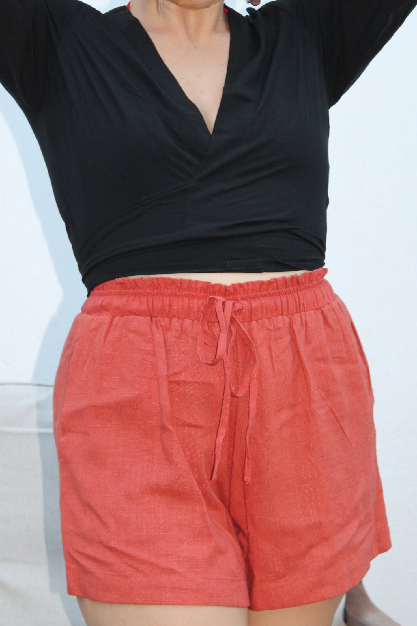 Black crop top with flared sleeves and red shorts.