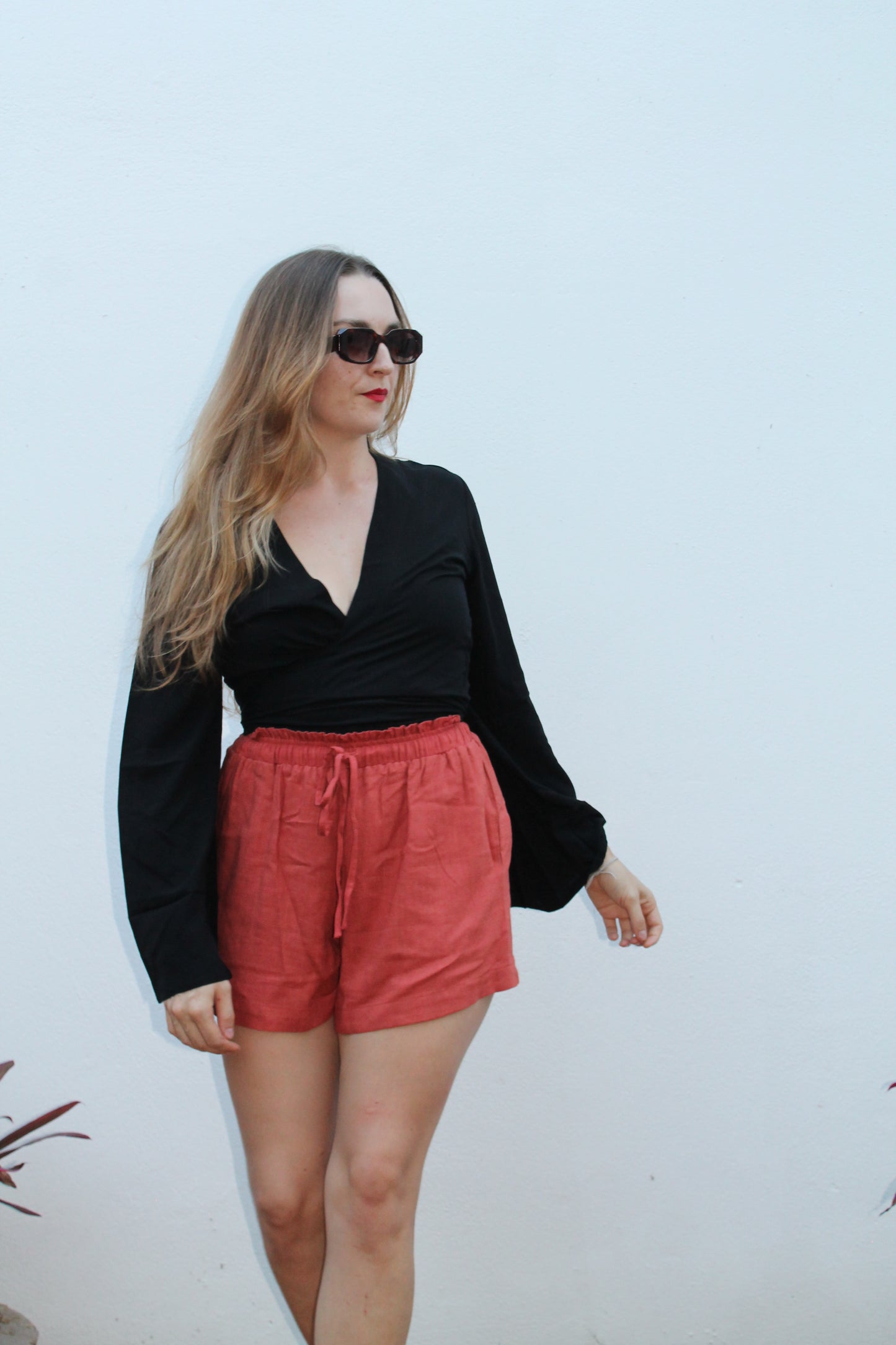 Black crop top with flared sleeves and red shorts.