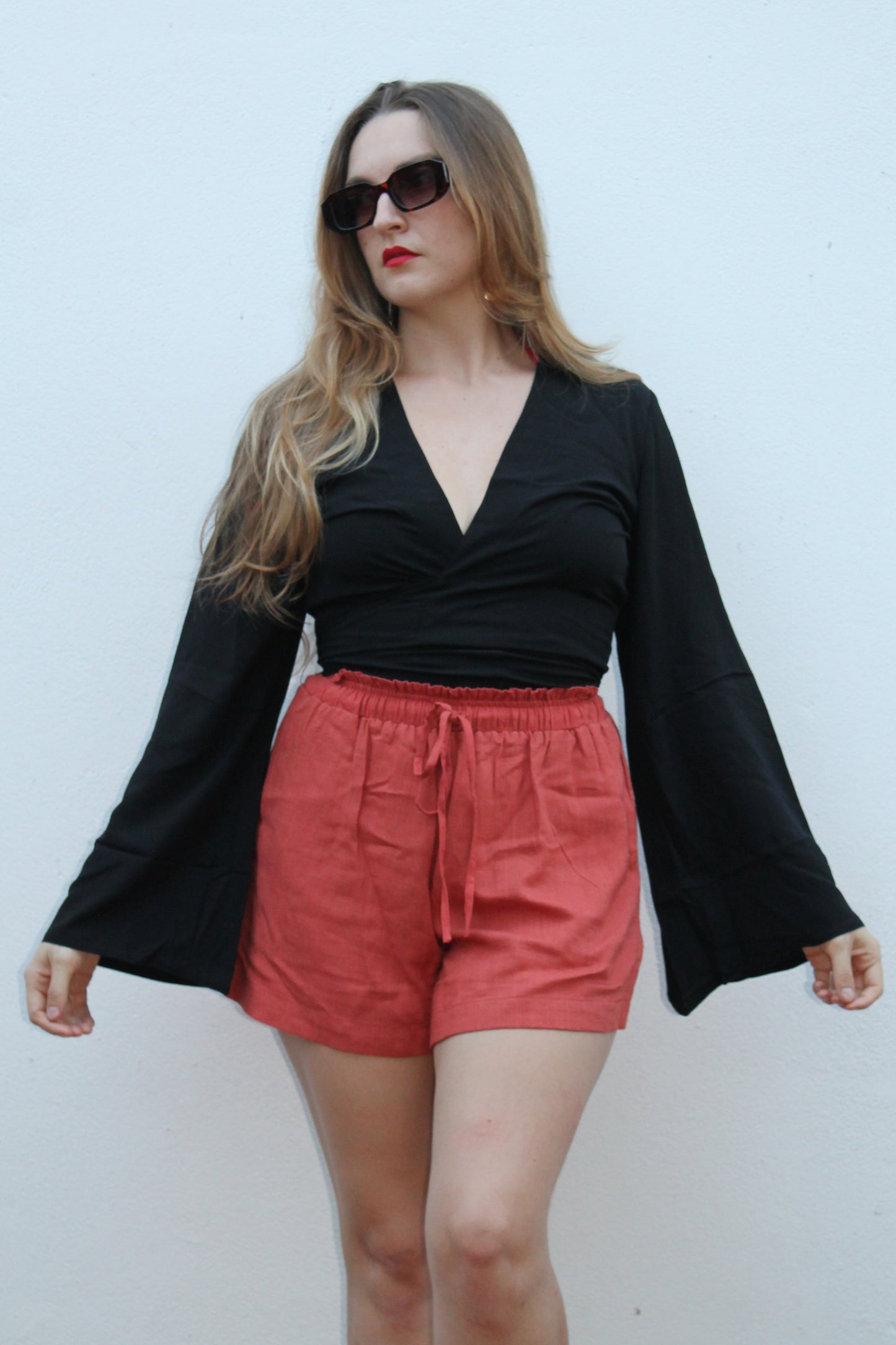 Black crop top with flared sleeves and red shorts.
