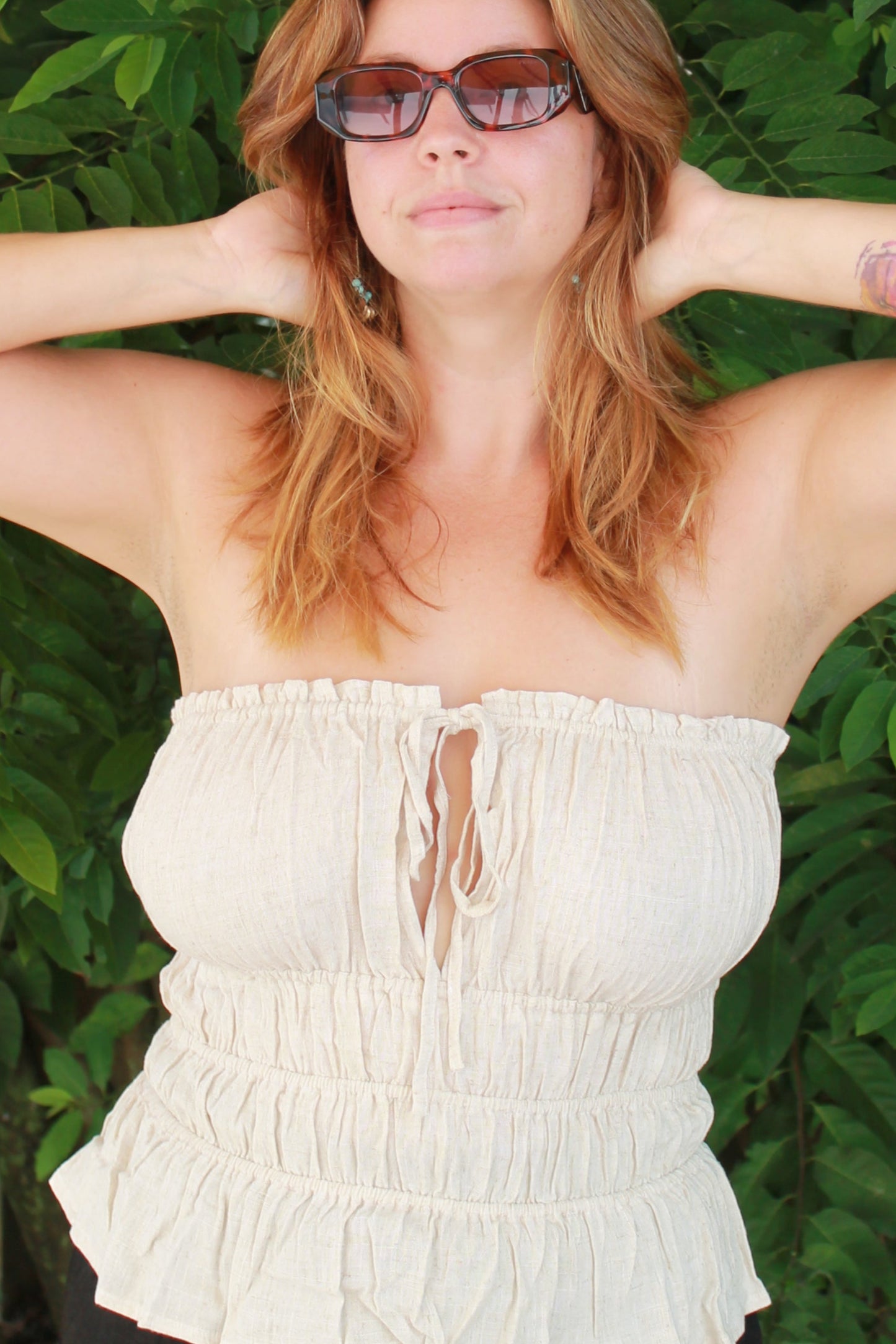 Woman in a white top with green foliage around her