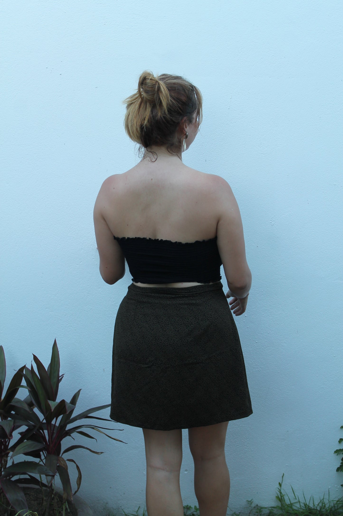 Person wearing a black dress with a white collar against a light blue background