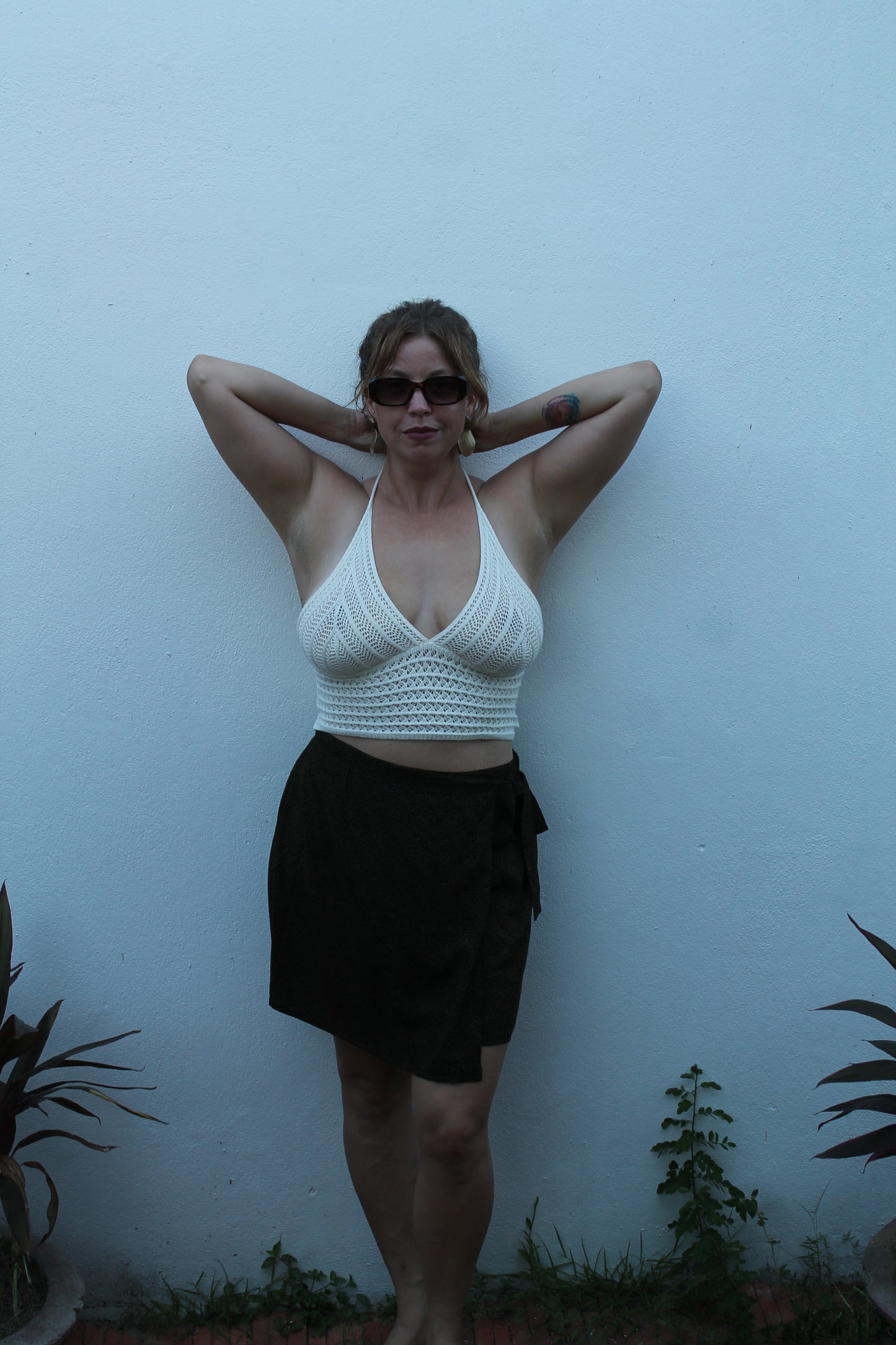 Person wearing a white woven crop top and mini skirt.
