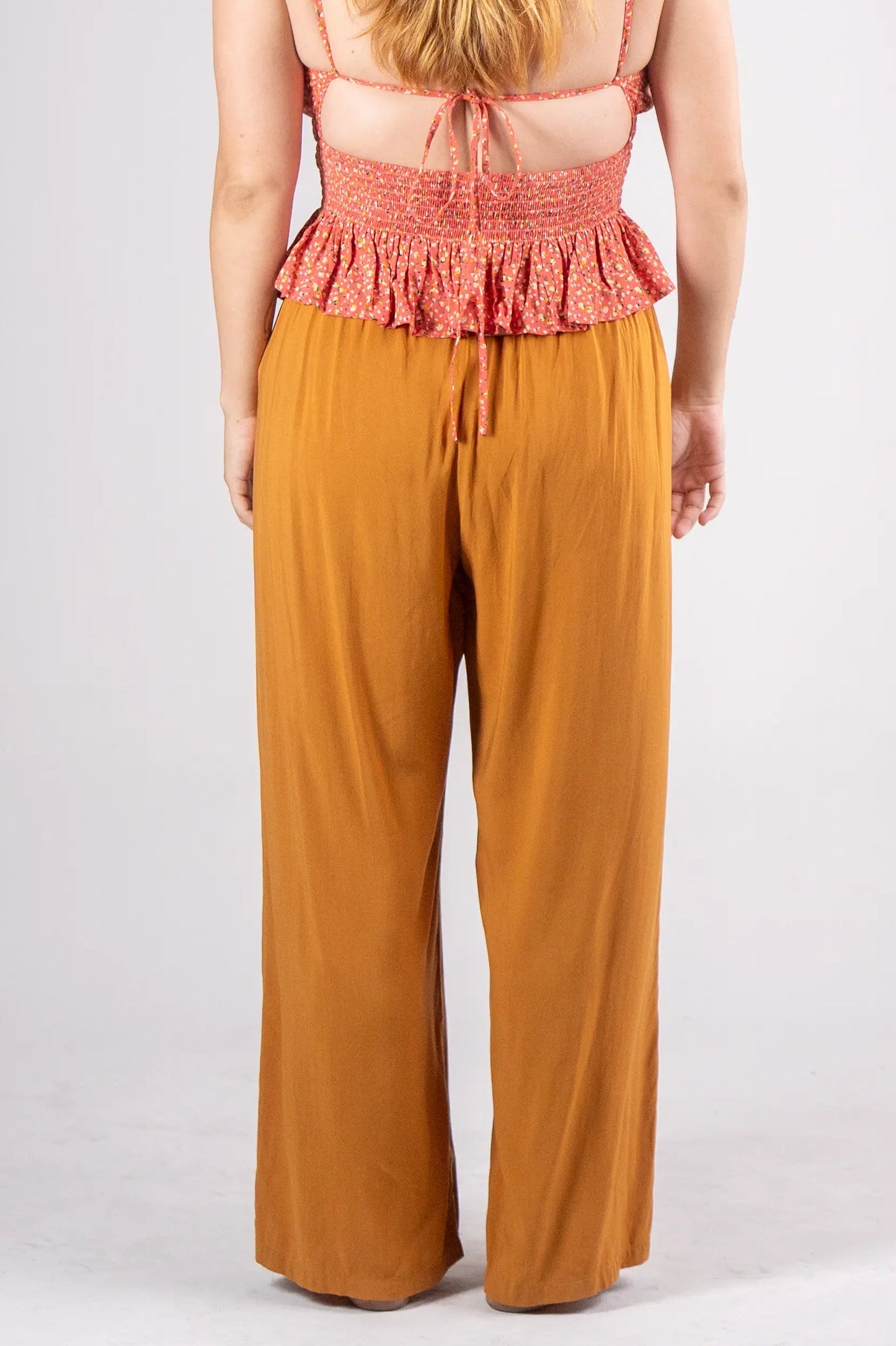 Woman wearing a red top and mustard yellow pants on a white background