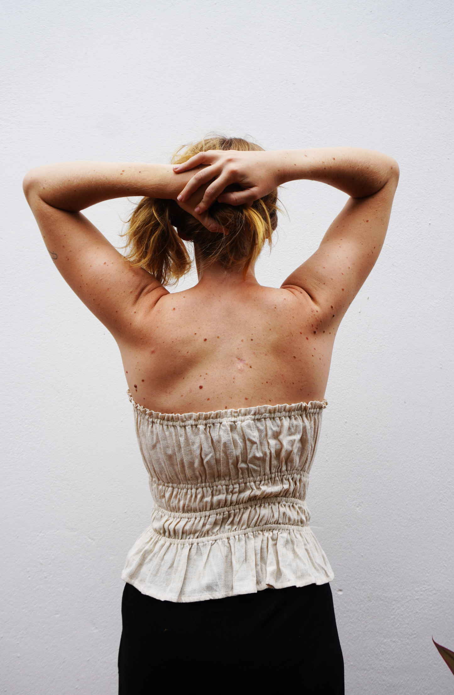 Person wearing a white strapless top with ruffled details against a plain background