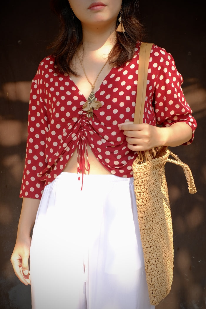 A woman wearing a red, cropped style top with polka dots.