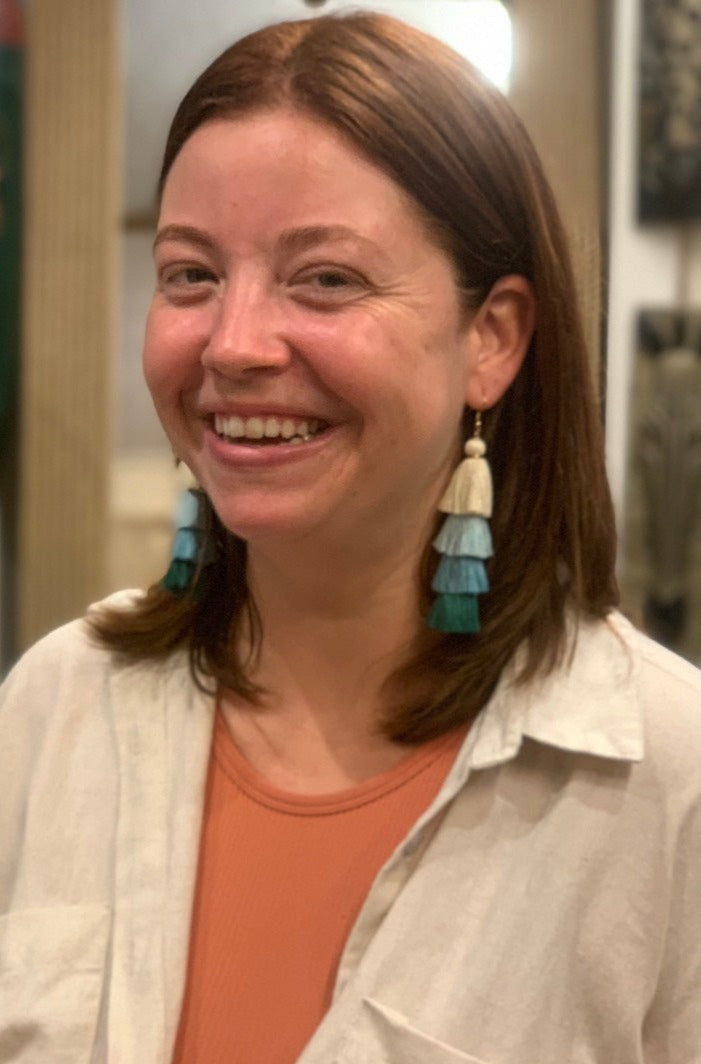 smiling woman wearing Blue tassel earrings.