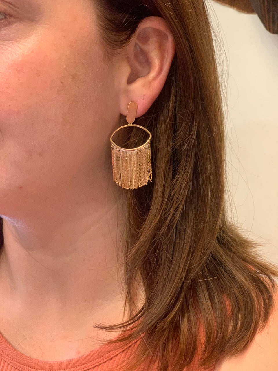 woman wearing boho style gold frilled earrings