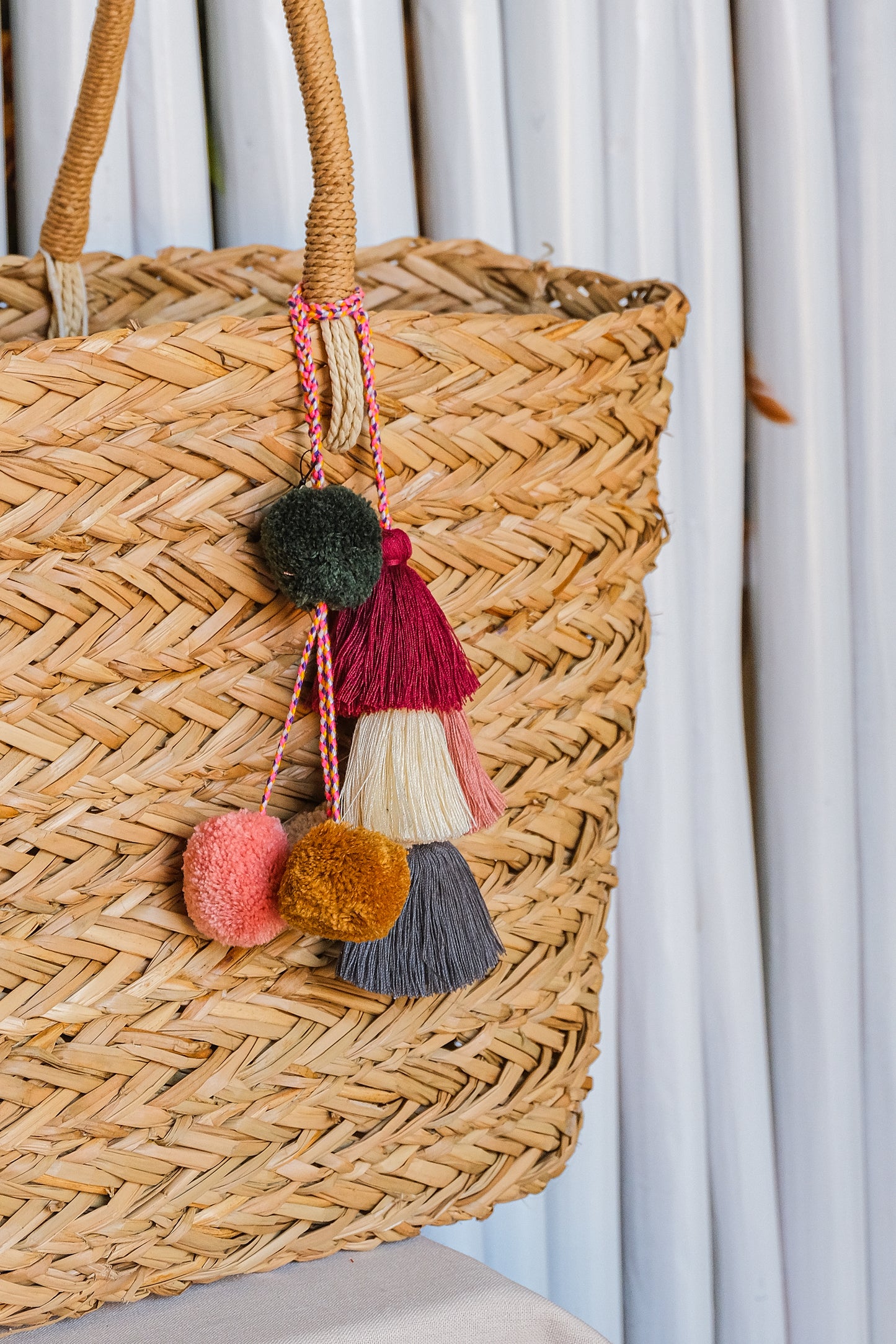 Woven basket with colorful tassels against a light curtain background