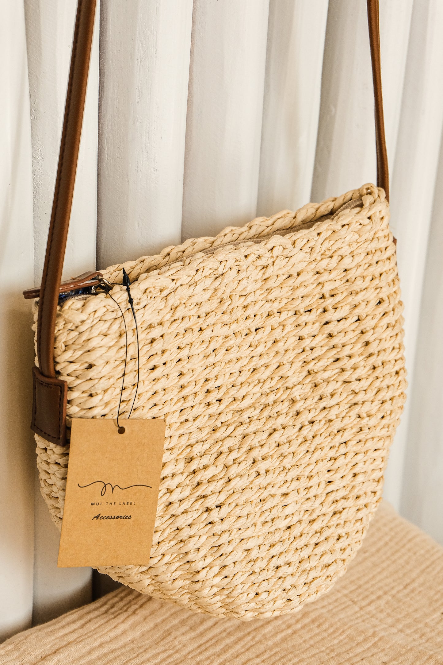 Woven handbag with a brown tag on a neutral background