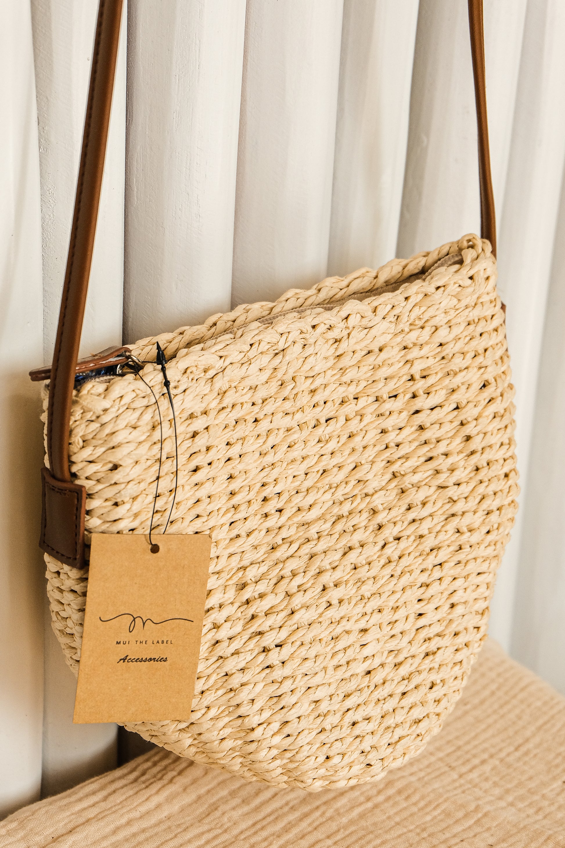 Woven handbag with a brown tag on a neutral background
