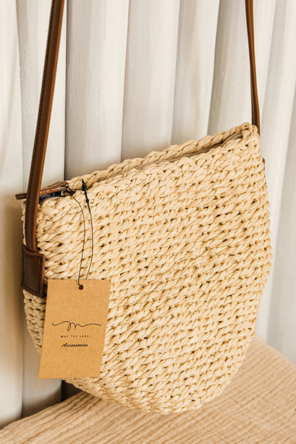 Woven handbag with a brown tag on a neutral background