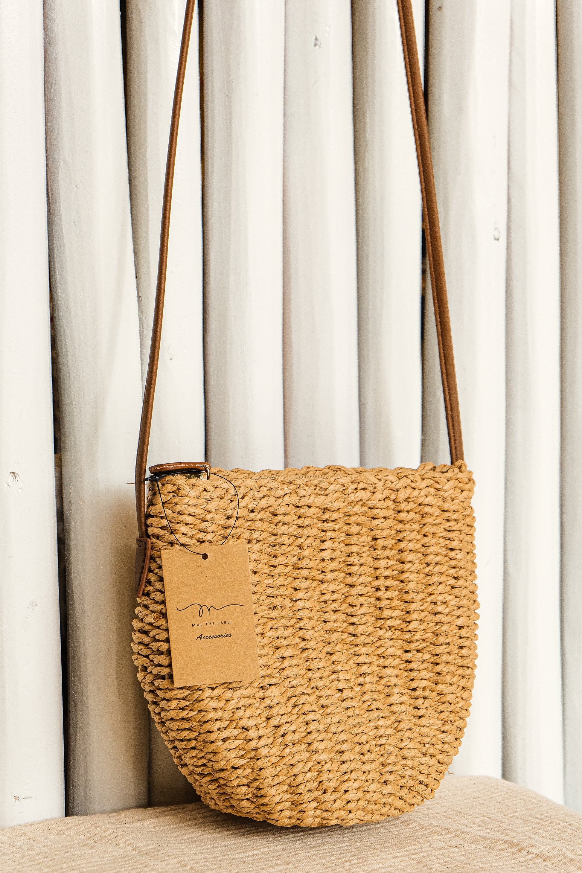 Woven handbag with a brown tag on a neutral background