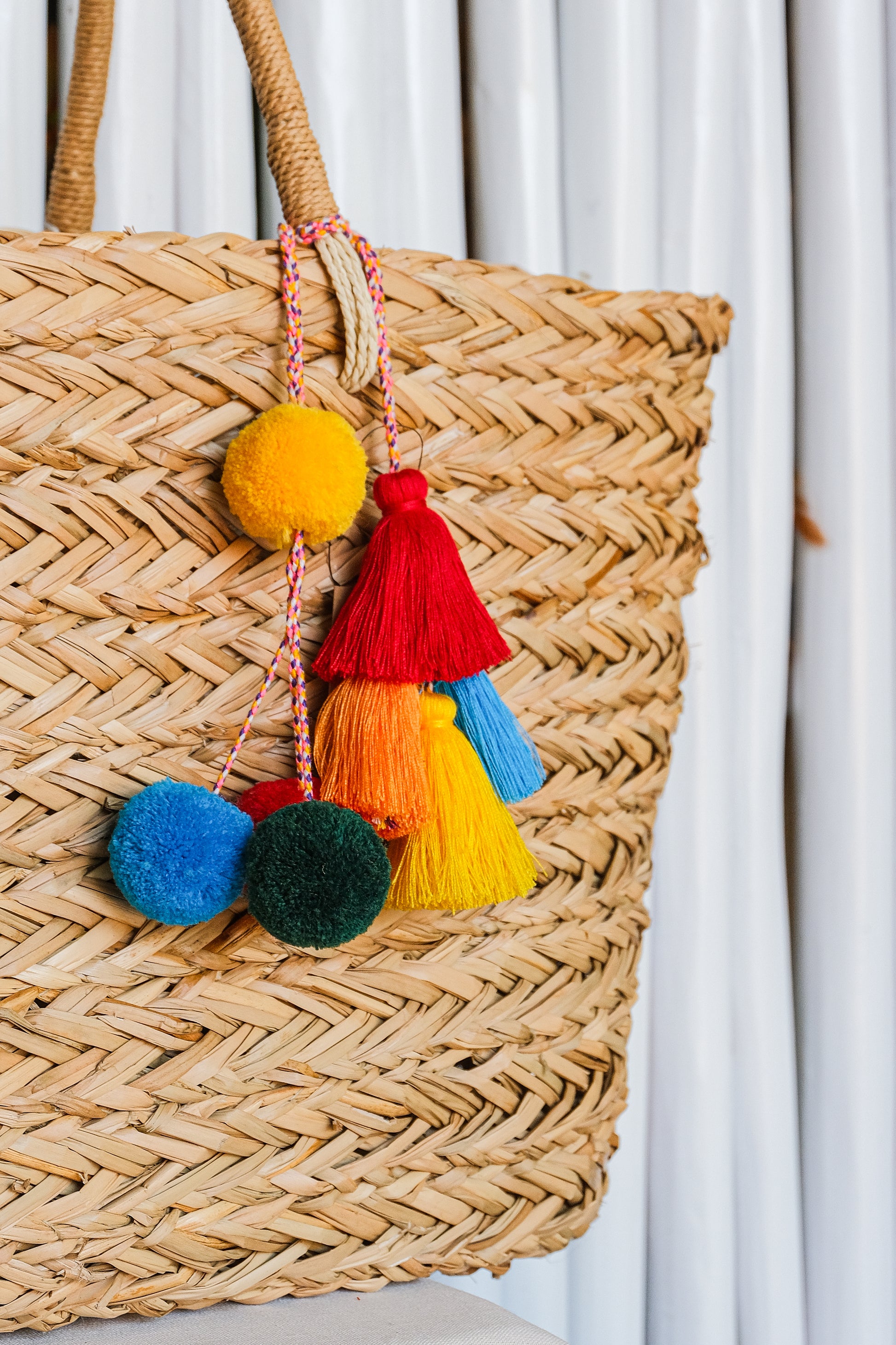 Colorful pom pom tassel keychain on a straw bag. 