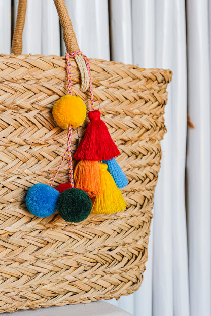 Colorful pom pom tassel keychain on a straw bag. 