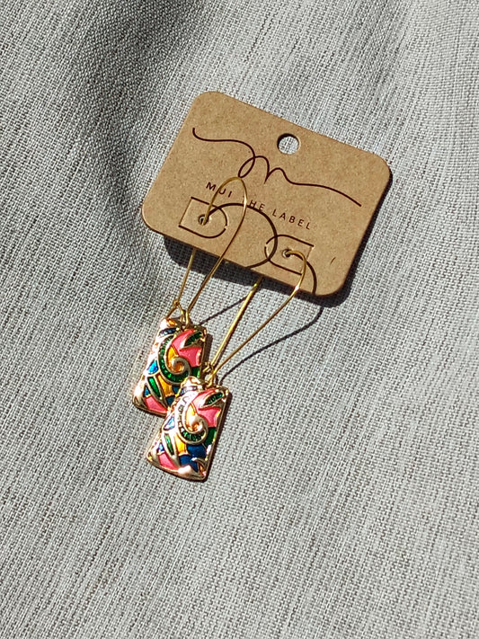 Colorful earrings on a branded card against a textured gray background