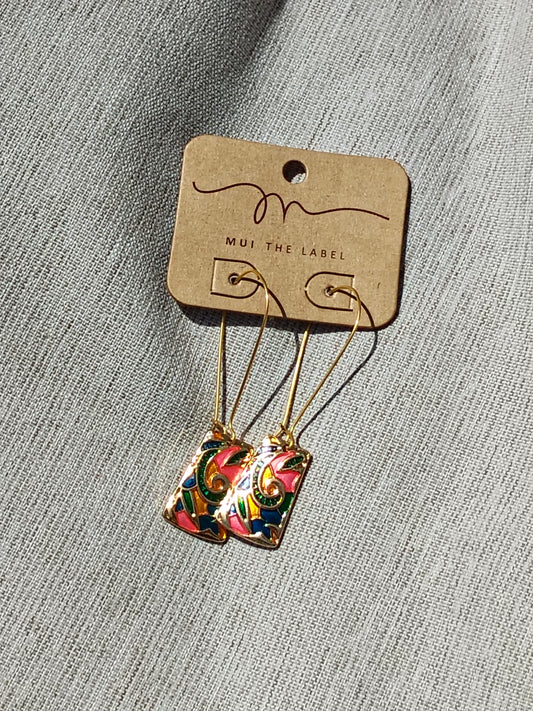 Floral earrings on a 'MUI THE LABEL' card against a gray background