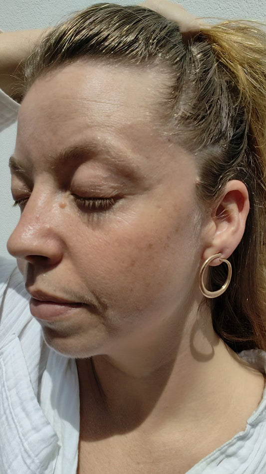Close-up of a woman with a gold hoop earring against a neutral background