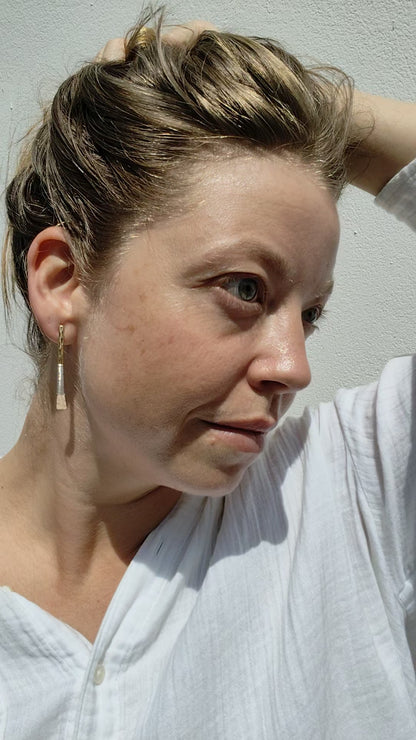 Woman wearing a gold earring against a light background