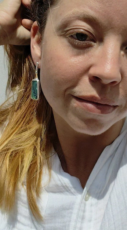 Close-up of a person wearing a pair of Mother of Pearl earrings with a neutral background