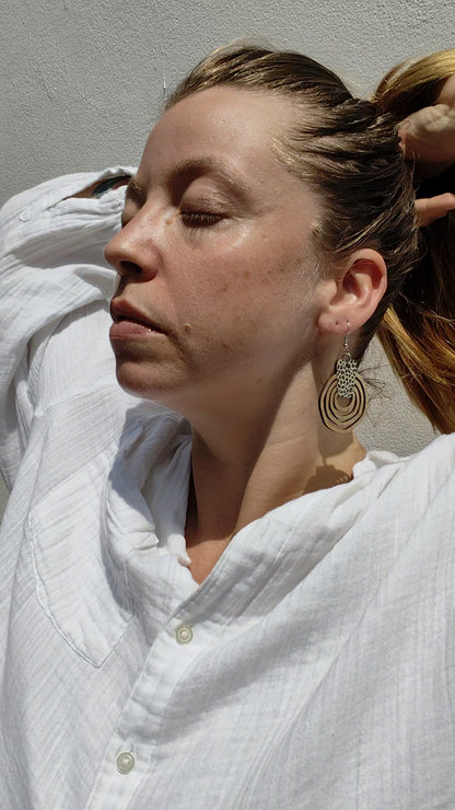 Woman wearing round wooden leopard print earrings. 