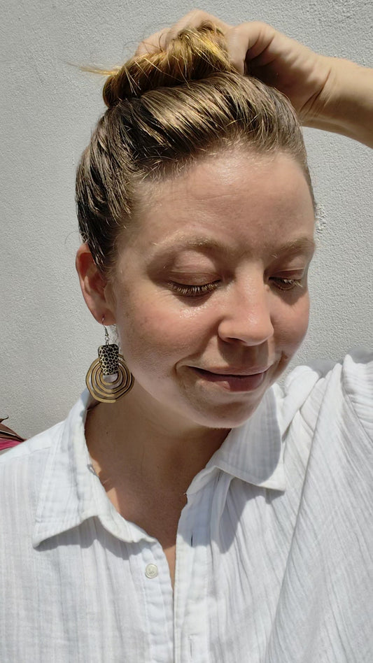 Woman wearing round wooden leopard print earrings. 