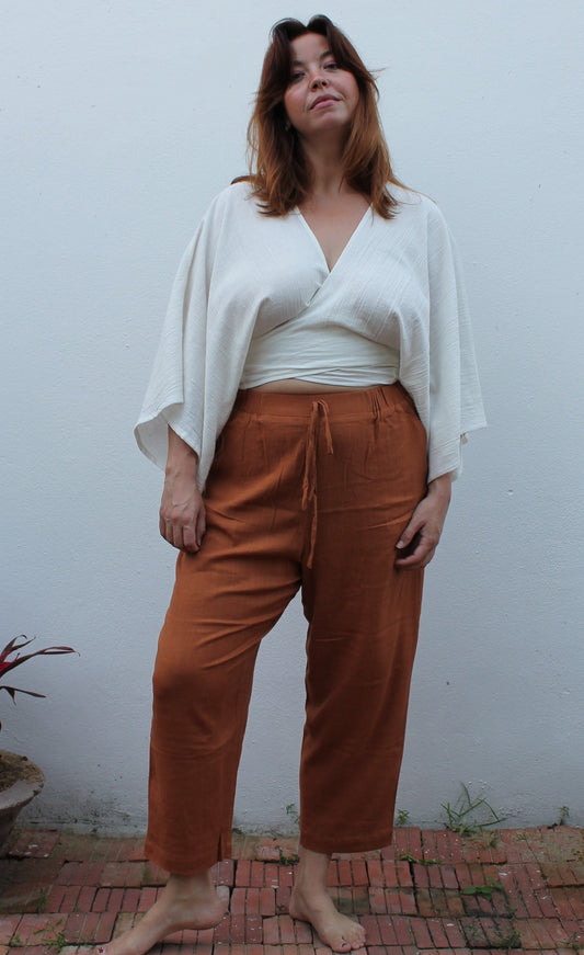 A boho style white wrap top and brown linen pants. 