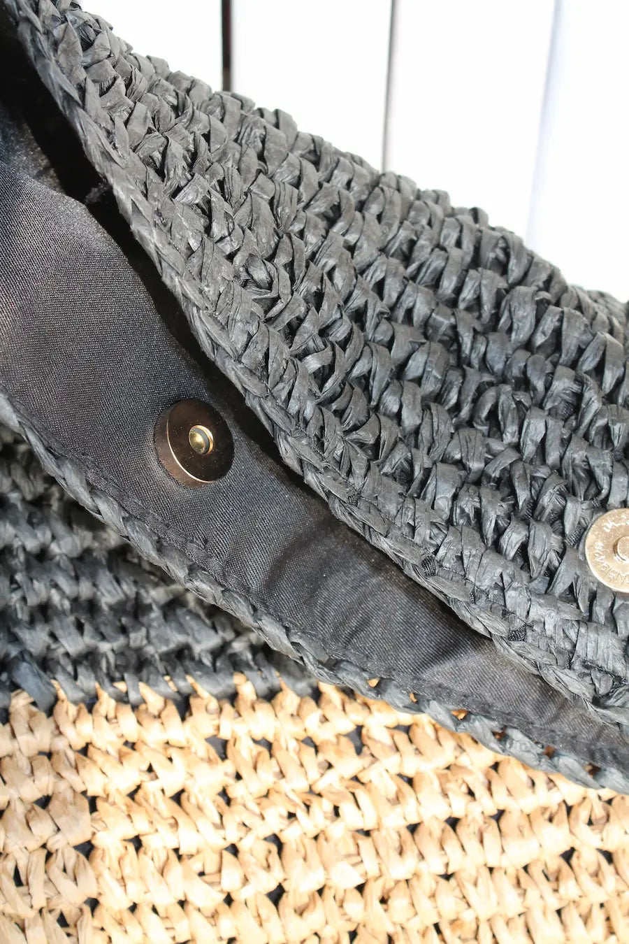 A woven bag with black and cream color block.
