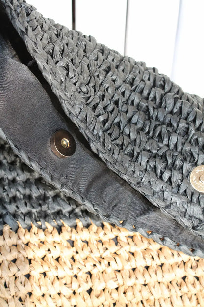 A woven bag with black and cream color block.