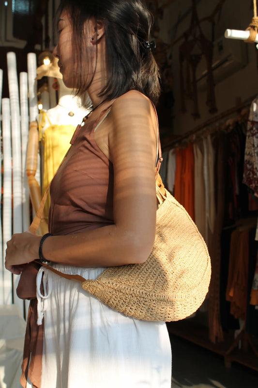 A brown woven sling bag. 