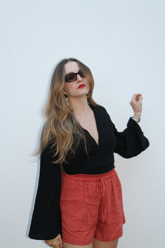 Black crop top with flared sleeves and red shorts. 