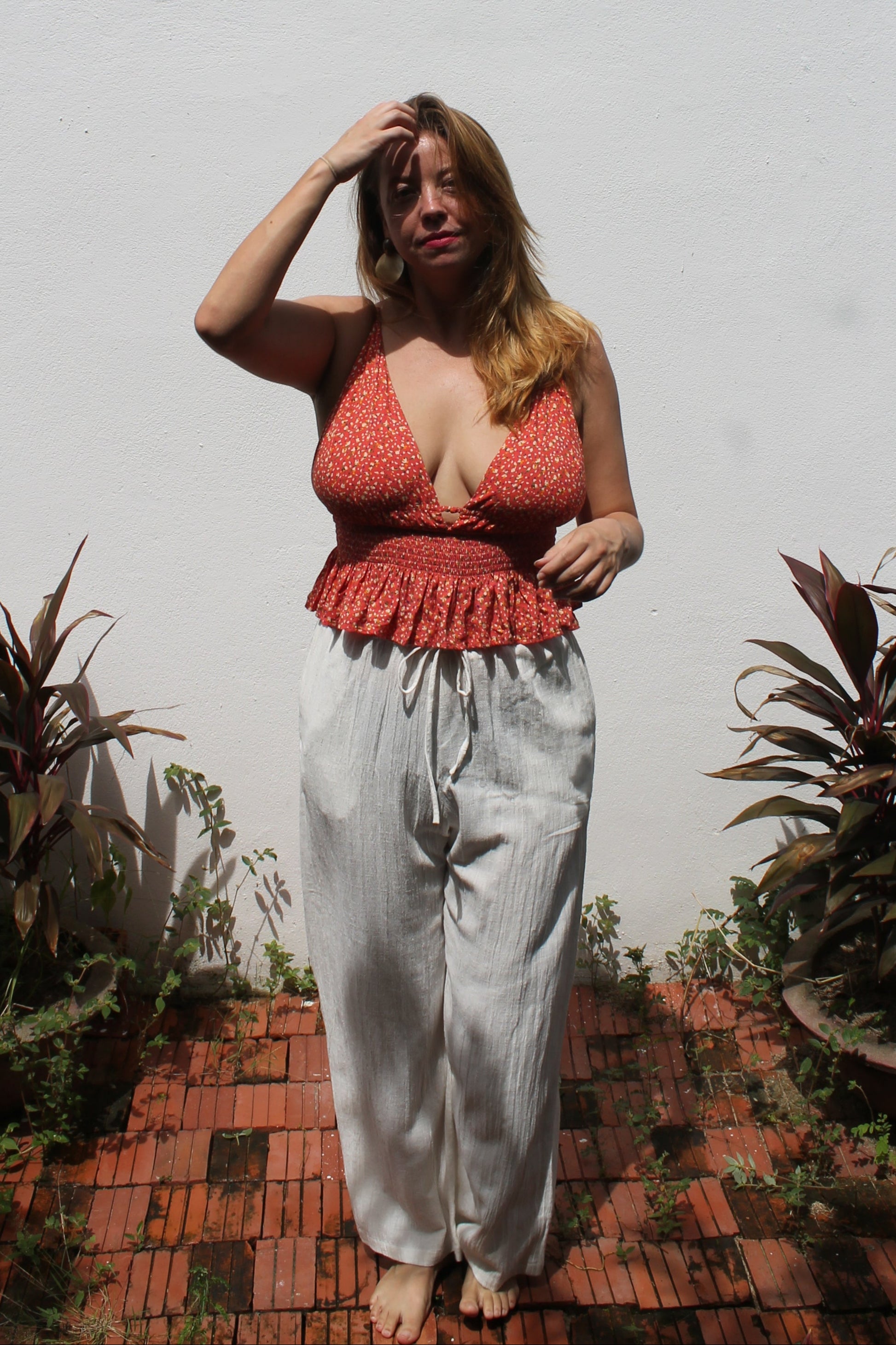Person in a red top standing on a white surface with plants around