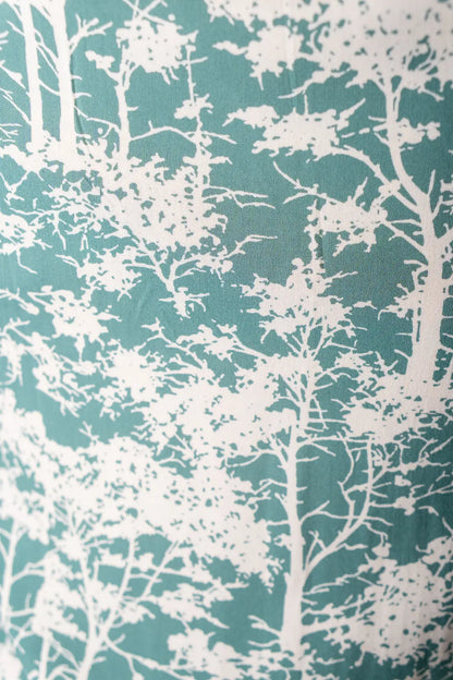 Fabric with white tree pattern on a teal background