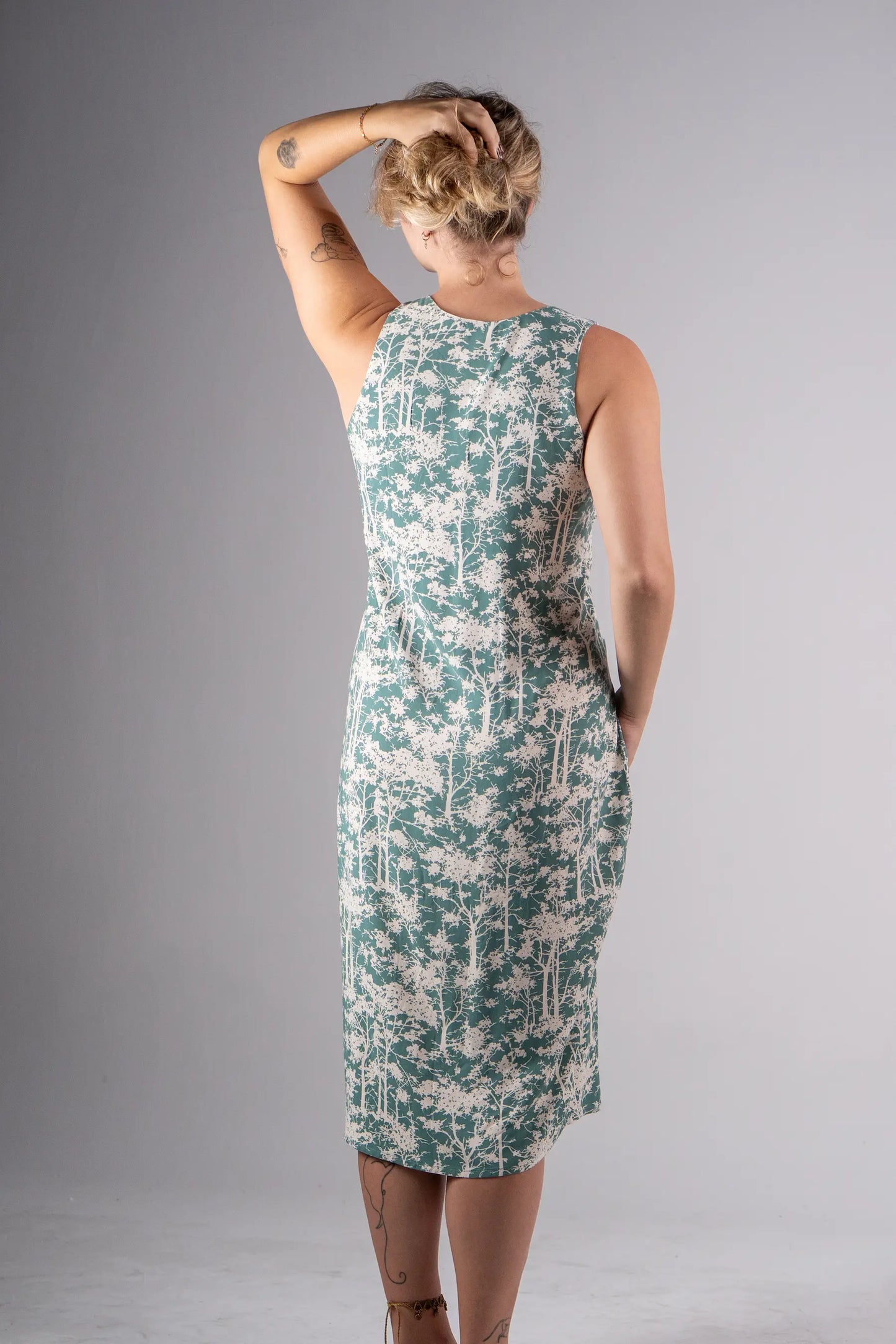 Woman wearing a green and white floral dress against a gray background