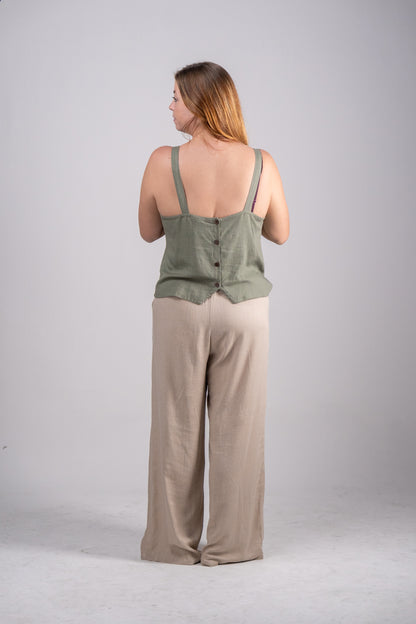 Woman wearing a green tank top and beige pants on a gray background