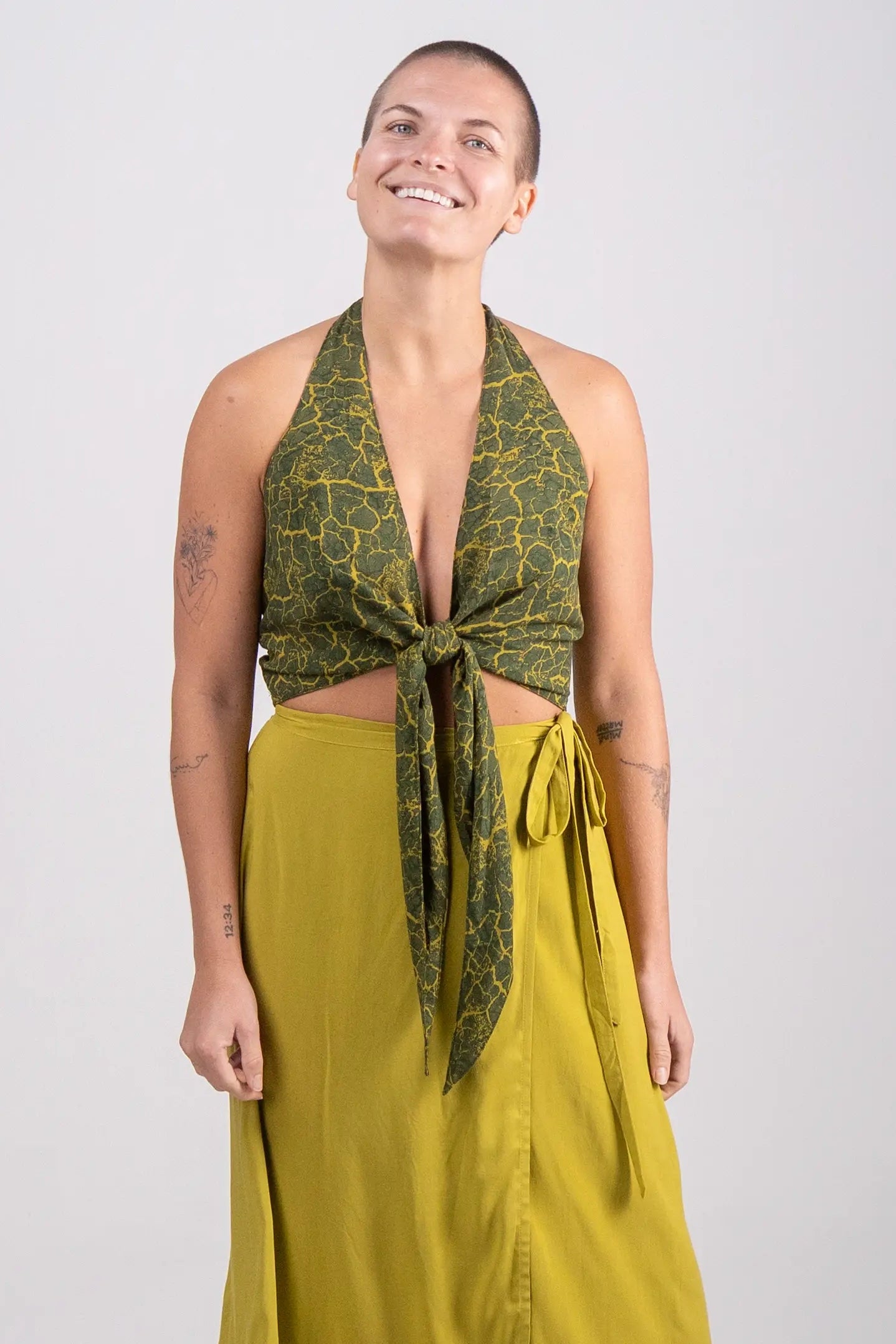 Woman wearing a green patterned top and yellow skirt on a white background