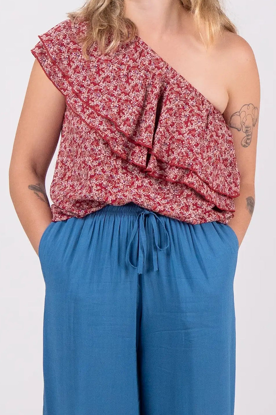 Woman wearing a red floral top and blue pants on a white background