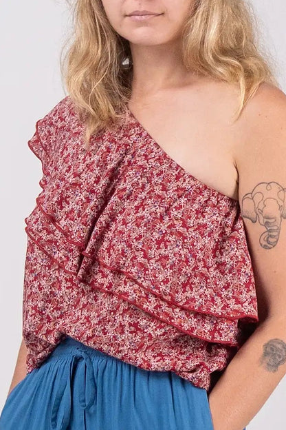 Woman wearing a red floral top and blue pants on a white background