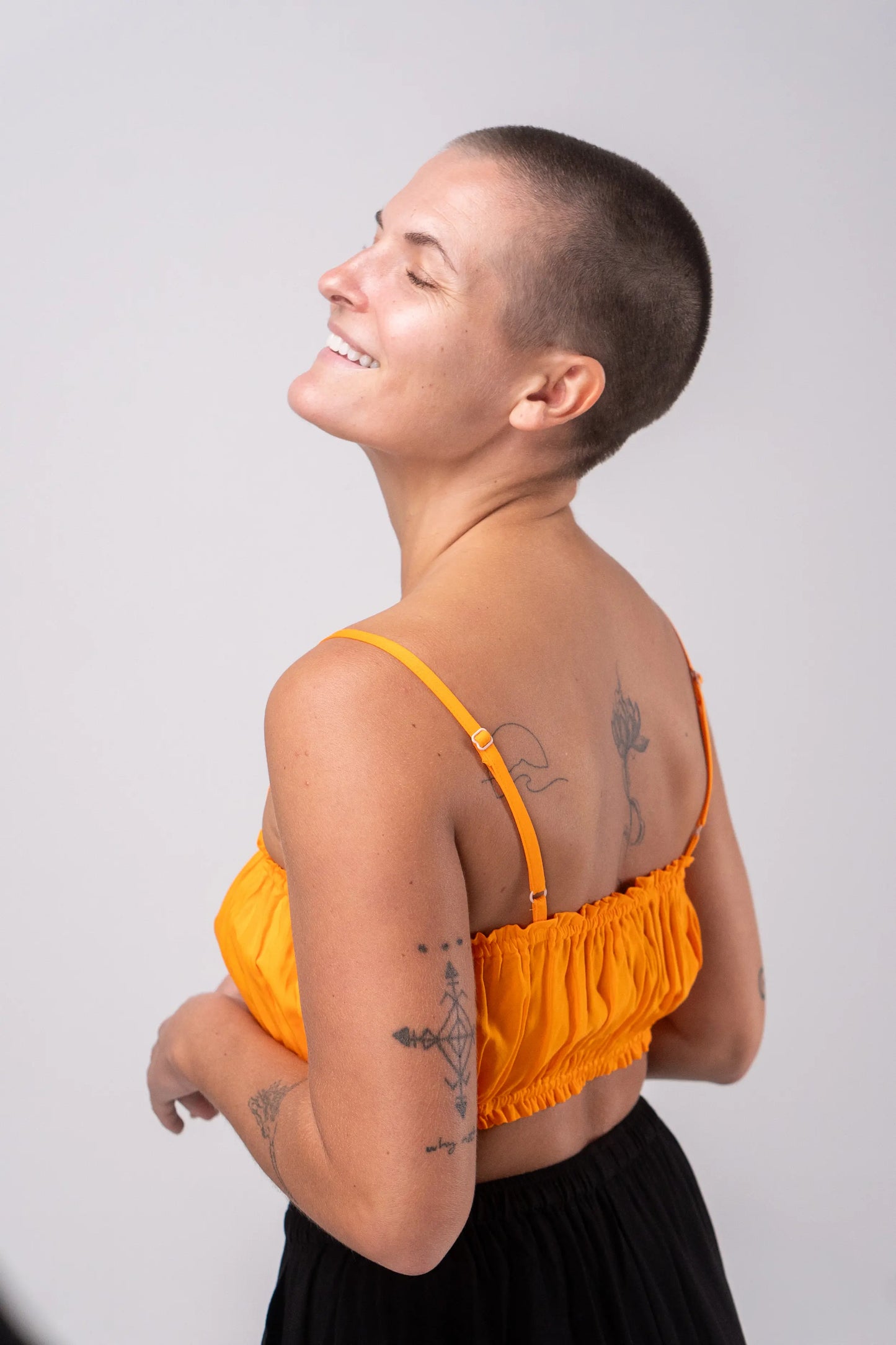 Person wearing an orange top with a plain background