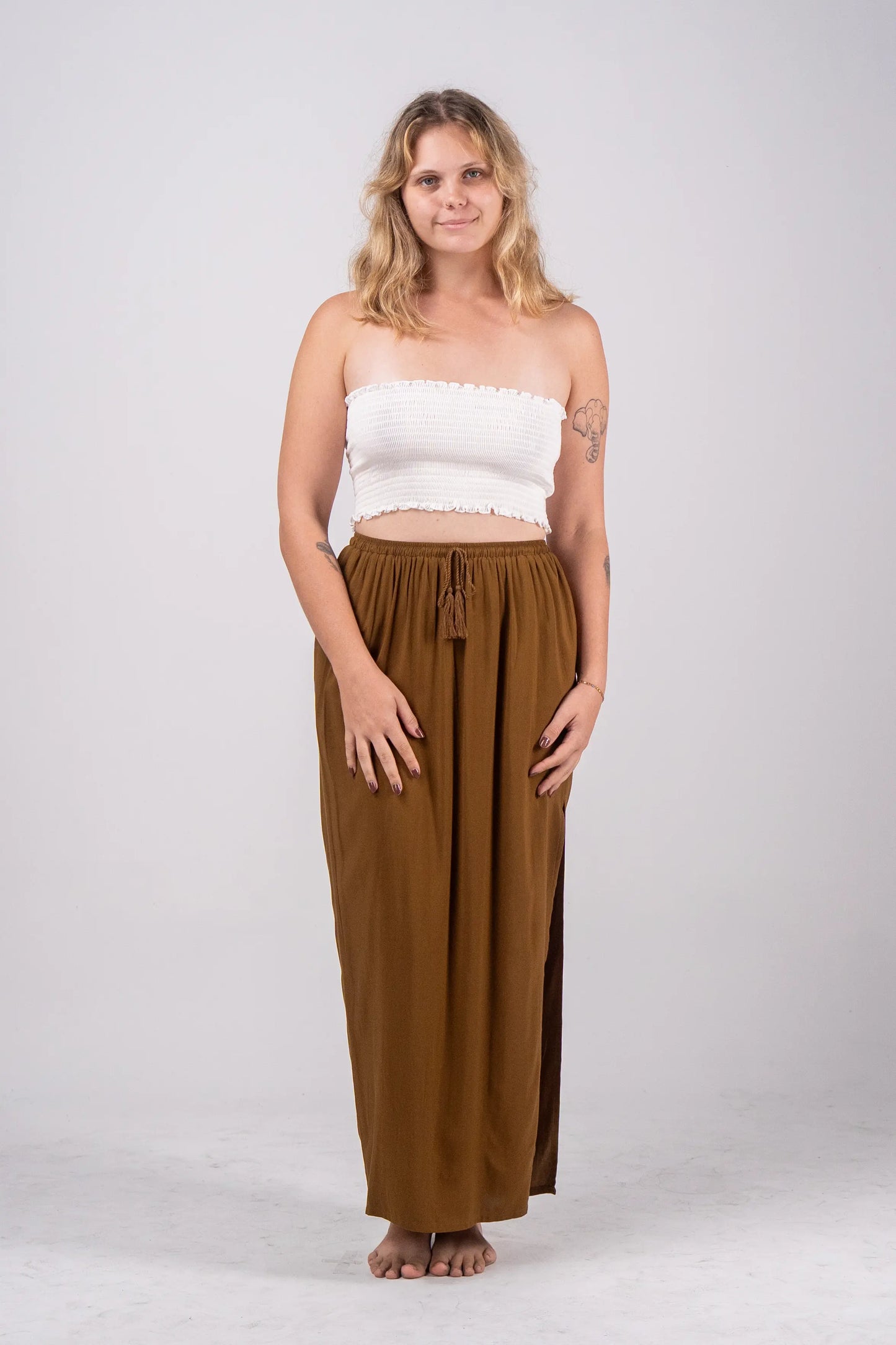 Woman wearing a white top and brown pants on a white background