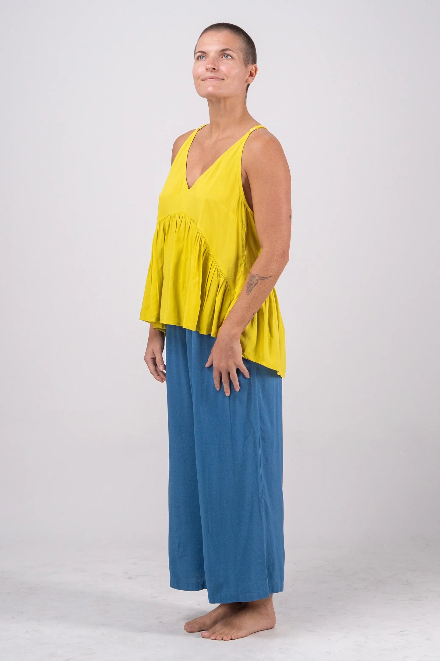 Woman wearing a yellow top and blue pants on a white background