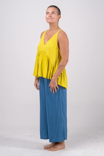 Woman wearing a yellow top and blue pants on a white background