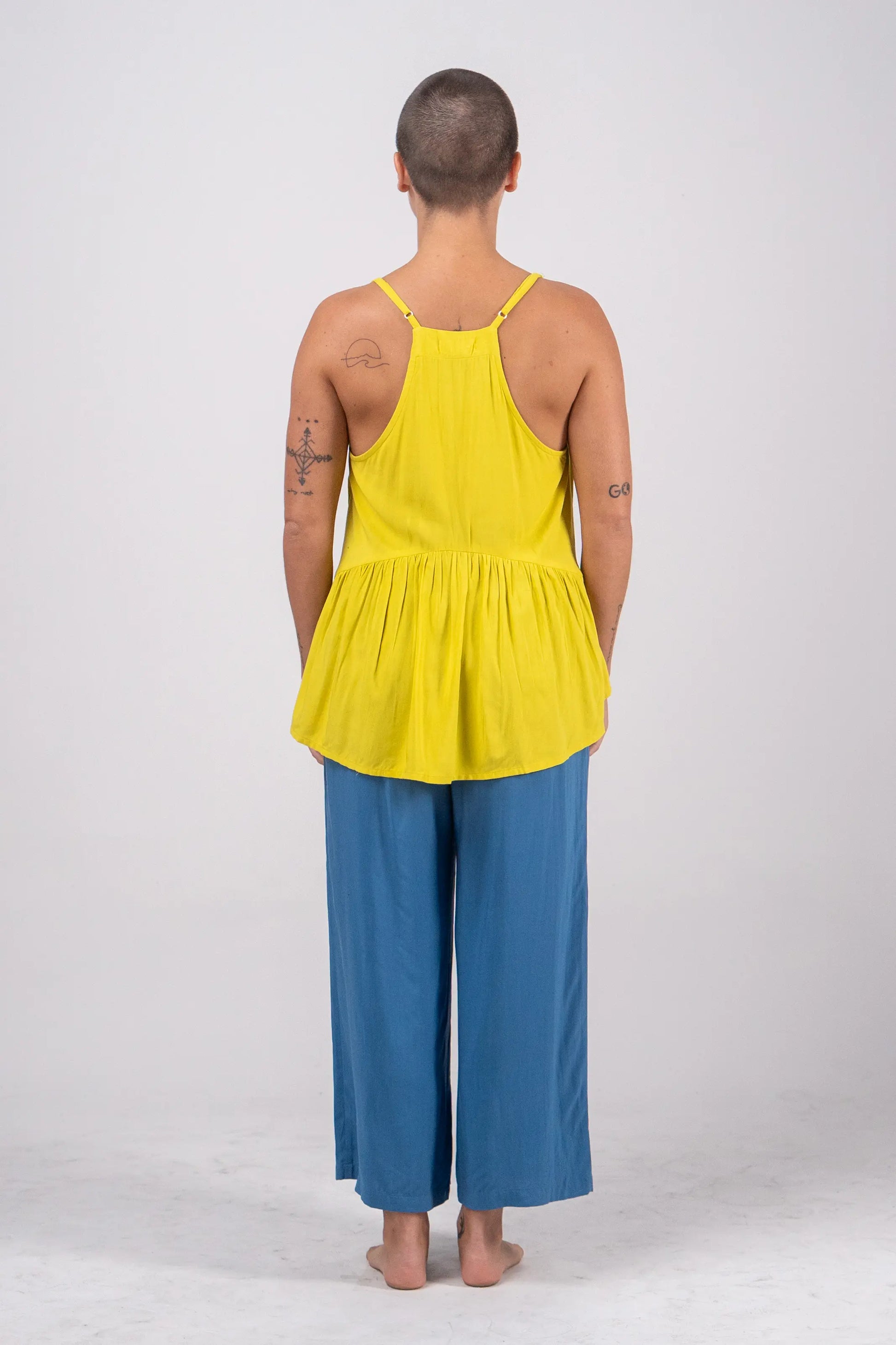Person wearing a yellow top and blue pants on a white background