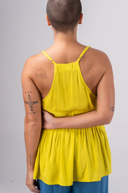 Person wearing a yellow tank top with blue pants on a gray background