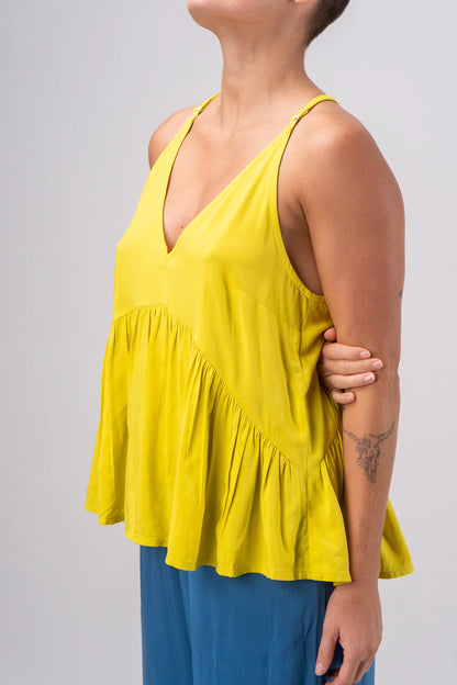 Yellow sleeveless top worn by a person on a plain background