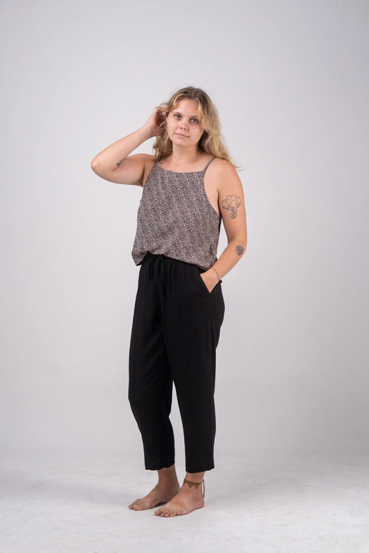 Woman wearing a patterned top and black pants on a white background